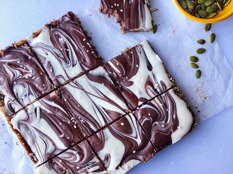 These healthy pumpkin bars made with pumpkin seeds, sunflower seeds, coconut flakes, dates, pink salt, and then topped with a chocolate swirl will make your day. These bars are gluten-free, grain-free, and refined sugar-free, as well as a no-bake! Make sure to make these pumpkin bars during thanksgiving and other occasions! Serve pumpkin (seed) bars as healthy snacks, dessert; make a lot, and freeze the remaining. #Pumpkin #Pumpkinbars #pumpkinseeds #sugarfree #grainfree #glutenfree #pumpkinrecipes