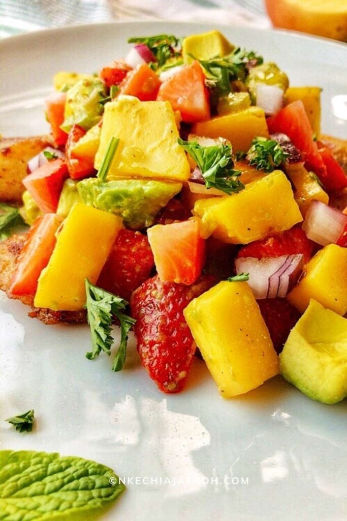Easy and most delightful mango strawberry avocado salad is fresh, flavorful, bright, crisp, and sweet! This salad is loaded with a combination of fruits and vegetables in season during the summer. A fruity salad you can serve with meat or fish for a more filling meal or use as salsa. Equally, this is one fresh and flavorful salad that you can load up on salad greens. Did I hear you say perfection? Yes, indeed! #Mangosalad #mangosalsa #Strawberrysalad #AvocadoSalsa #easysalad #summertime #summersalad #20minutemeal #fruitsalad  
