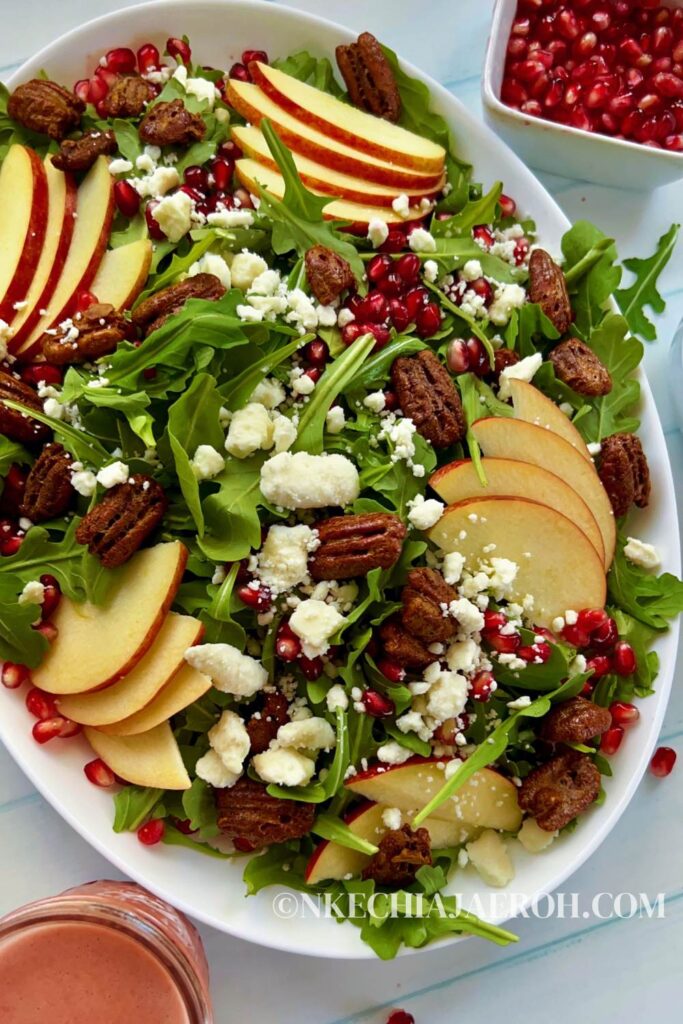 Healthy pomegranate arugula salad with apples and pecans is easy to make, pretty, and perfect for any occasion! My pomegranate salad bursts with delicious flavors from the slightly spiced arugula, sweet and crisp apples, and crunchy pecans. This easy salad is bejeweled with fresh pomegranate seeds or arils and finished with pomegranate salad dressing. This would make an enviable summertime salad recipe as well!  #Pomegranatesalad #arugulasalad #pomegranate #salad