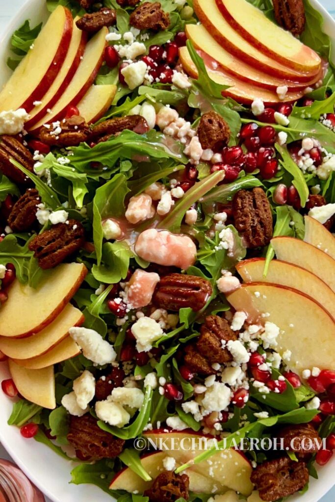 Healthy pomegranate arugula salad with apples and pecans is easy to make, pretty, and perfect for any occasion! My pomegranate salad bursts with delicious flavors from the slightly spiced arugula, sweet and crisp apples, and crunchy pecans. This easy salad is bejeweled with fresh pomegranate seeds or arils and finished with pomegranate salad dressing. This would make an enviable summertime salad recipe as well!  #Pomegranatesalad #arugulasalad #pomegranate #salad