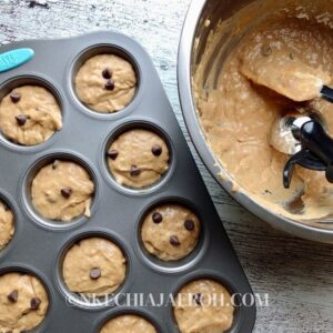 Grease the cupcake tins with oil spray, butter, or olive oil. Using an ice cream scoop, add the batter to the baking tins. Top with a few more chocolate chips; this is optional. This makes up to 16-19 muffins.