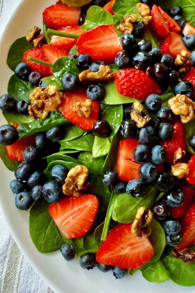 Super healthy and easy-to-make strawberry blueberry spinach salad, aka berry spinach salad with lime olive oil vinaigrette, is loaded with nutritious antioxidants, vitamins, and minerals. Amazingly this spinach and berry salad calls for only a few ingredients - spinach, strawberries, blueberries, walnuts, and a simple lime olive oil vinaigrette! This strawberry blueberry spinach is low-carb, gluten-free, vegan, and easily customizable. #Salad #Spinachsalad #healthysalad #Strawberrysalad #detoxsalad #vegan #lowcarb