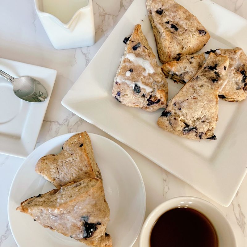 There are scones, and then there are these super sweet + nutritious blueberry scones made with frozen ripe blueberries. Wishing you could just eat those blueberry scones you saw at the bakery? Let me show you how to make your own with the sweetest and most nutritious blueberry scones recipe EVER! Made with frozen berries, you won’t have to wait for berry season to enjoy these. If you have ever had a scone before you know that you typically smash butter, cream, or fruit sauce or preserve on them but not this one! These melt-in-your-mouth blueberry scones are super sweet, rich, and decadent, and no extra accompaniment is needed. You will never get any scones here on the streets that are better than these.
