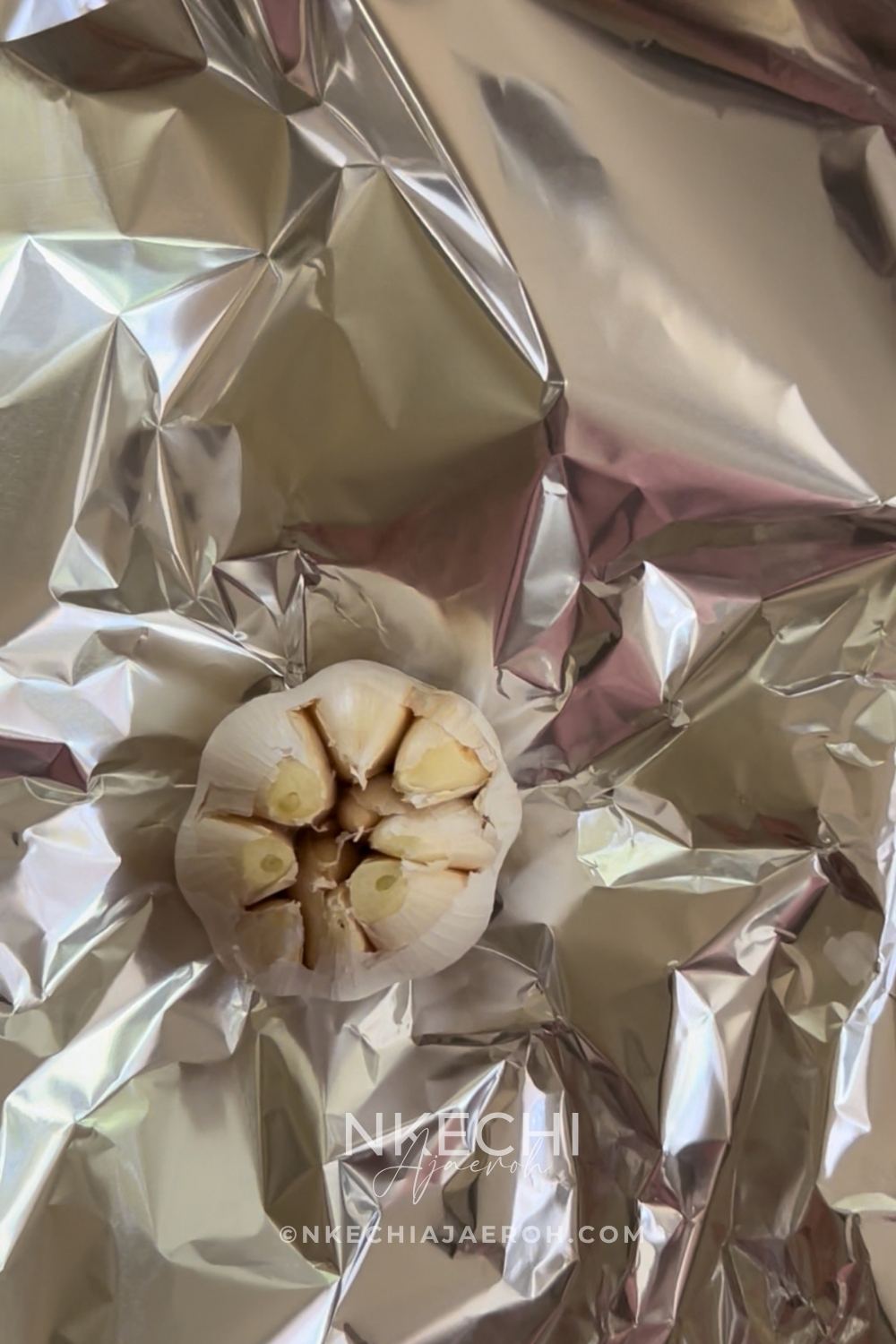 Remove the loose skin from the top of the garlic head, exposing the fresh garlic. Place the garlic head on a piece of foil or parchment paper and season with salt and olive oil. Wrap it up and place it on the same baking sheet alongside the butternut squash, covering it with foil.