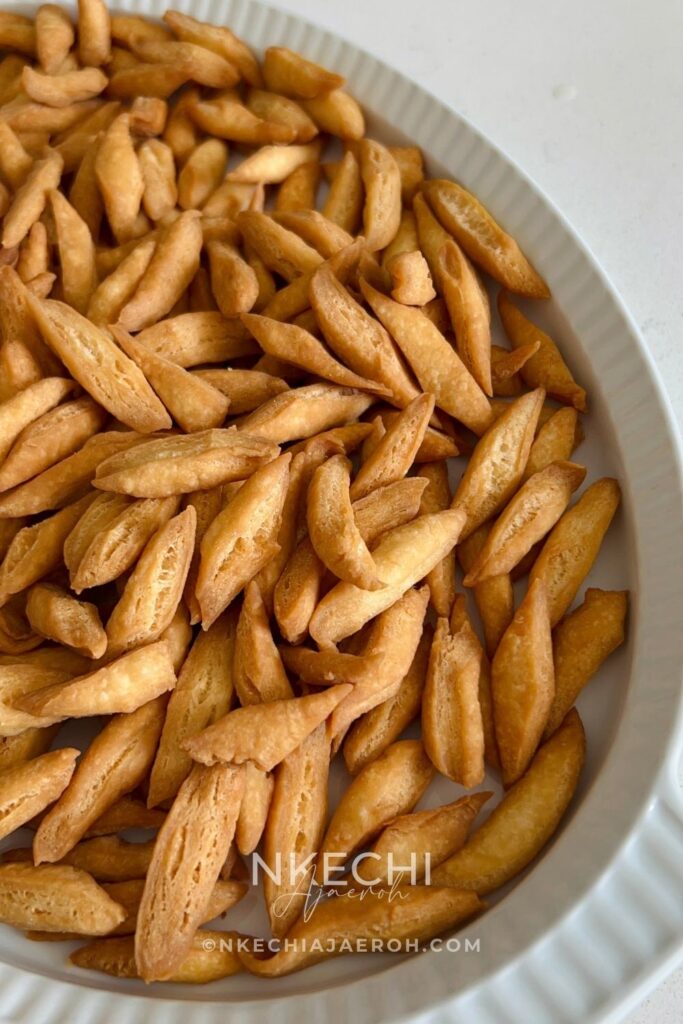 Nigerian chin chin is a popular West African snack known for its crunchy texture, buttery flavor, and lightly sweet taste. Made from a simple dough of flour, butter, sugar, eggs, and nutmeg, chin chin is rolled, cut into small pieces, and fried until golden and crisp. This classic snack is a staple at holidays, birthdays, weddings, and family gatherings, and it’s just as common to find it sold as street food. Chin chin stays crunchy for days and is easy to make in large batches, which makes it perfect for sharing and gifting.
Depending on how long it’s fried, chin chin can range from light golden to deep brown, with each shade offering a satisfying crunch. For many Nigerians and West Africans, chin chin isn’t just a snack — it’s a nostalgic treat that brings back memories of growing up and celebrating together.