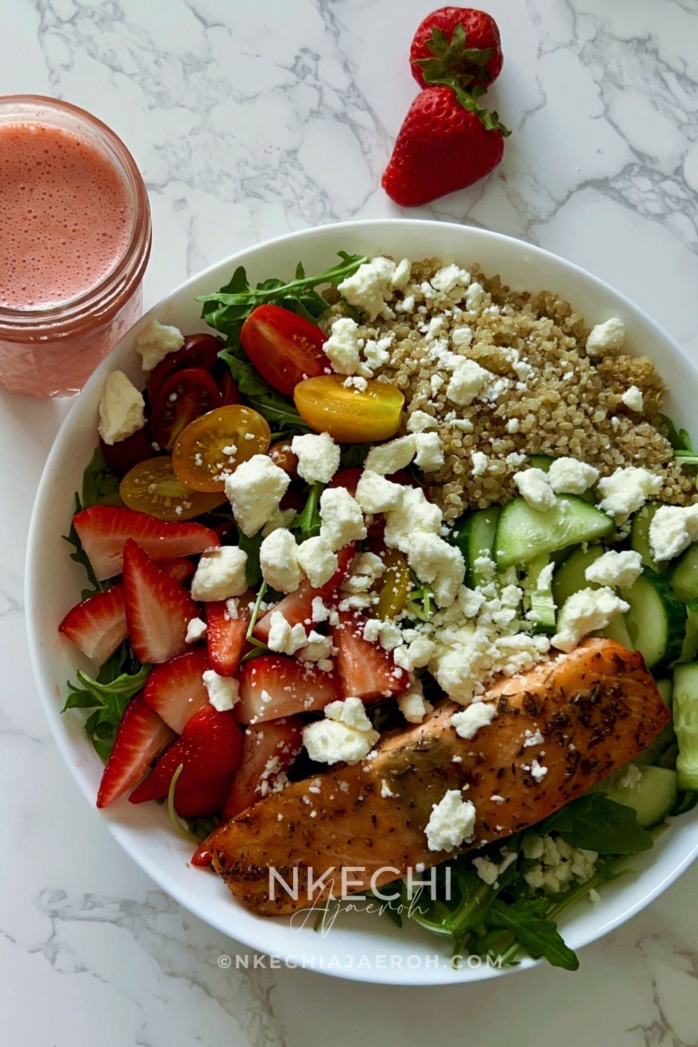 Add the arugula to a large serving bowl. Top with the cooked quinoa, strawberries, cucumbers, cherry tomatoes, and crumbled feta cheese. Place the warm salmon on top. I suggest drizzling the homemade strawberry dressing only when you are ready to eat.